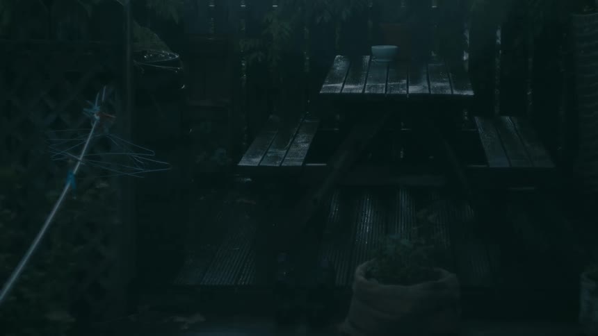 Outdoor area with wooden tables and benches wet from rain in a dark setting