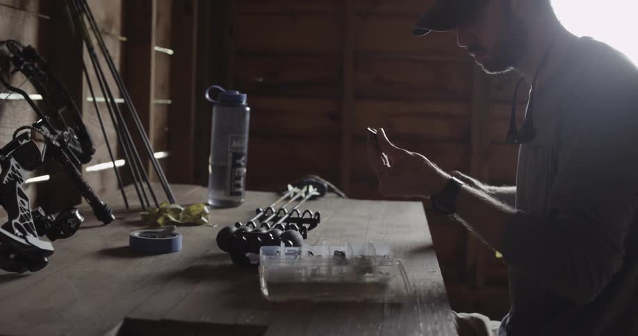 A hunter adjusts the tip of an arrow