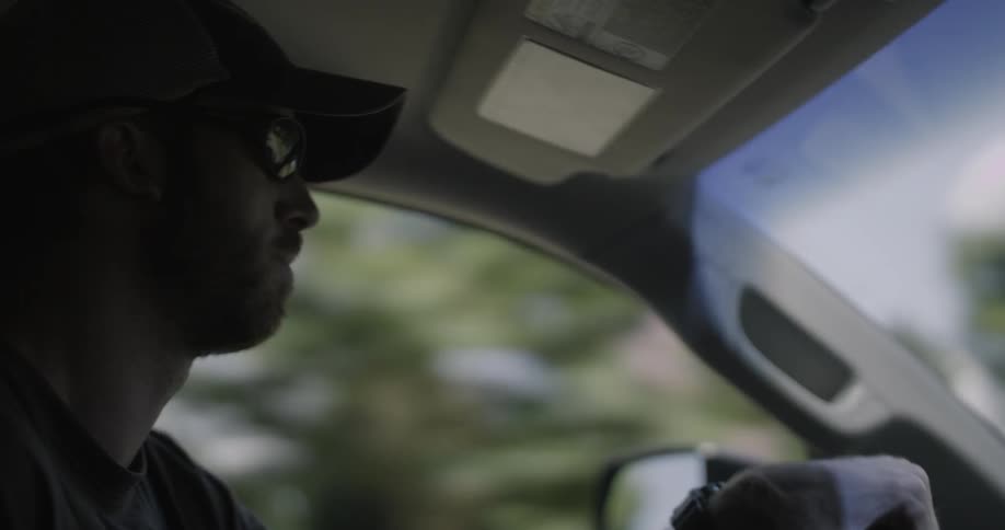 A man drives a car with trees outside