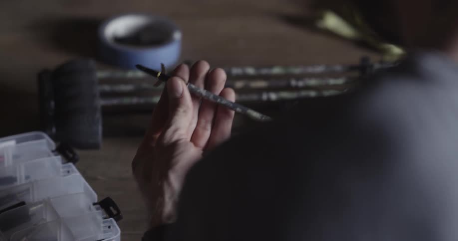 A man is working on assembling bow arrows