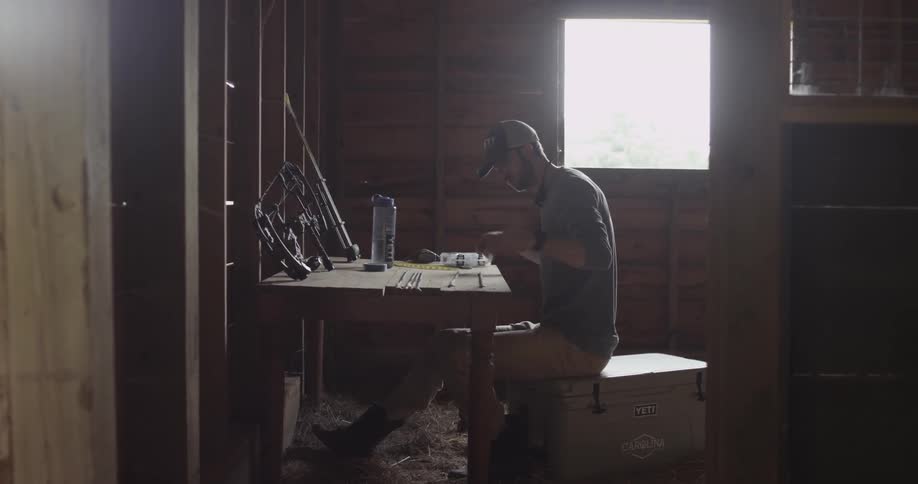 A hunter sits at a table in a workshop