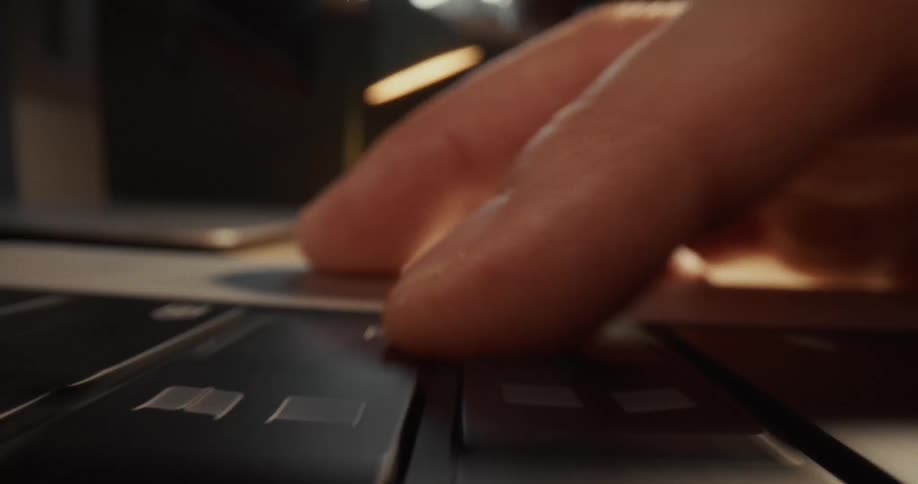 A close up view shows a dramatic zoom of a person pressing a key on a laptop keyboard