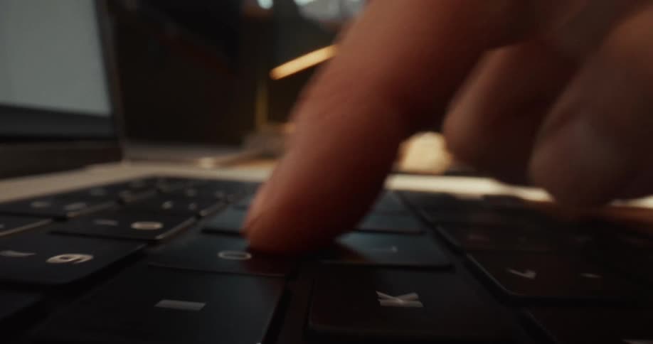 Closeup of finger pressing keys on a laptop keyboard in a modern workspace