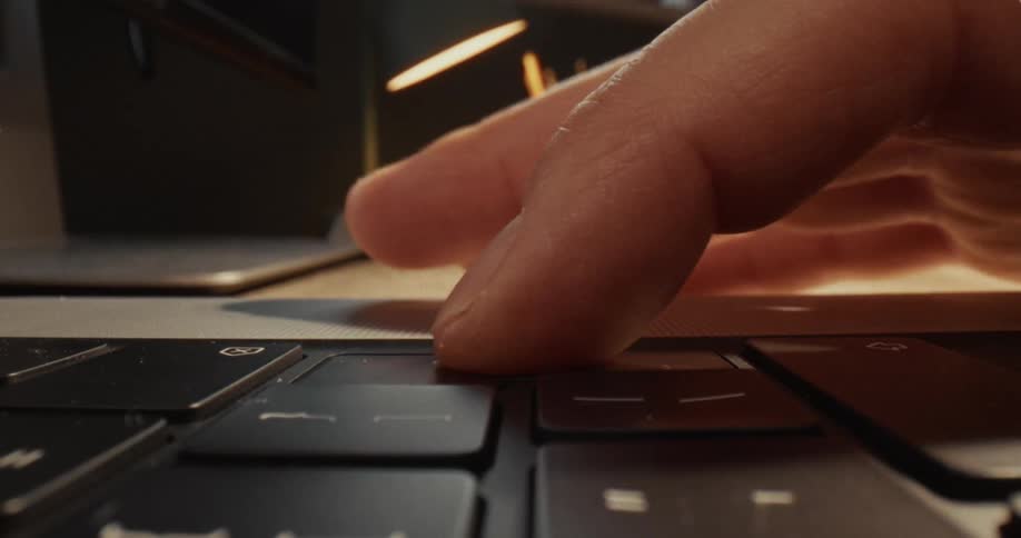 Finger pressing a laptop keyboard key on a work desk