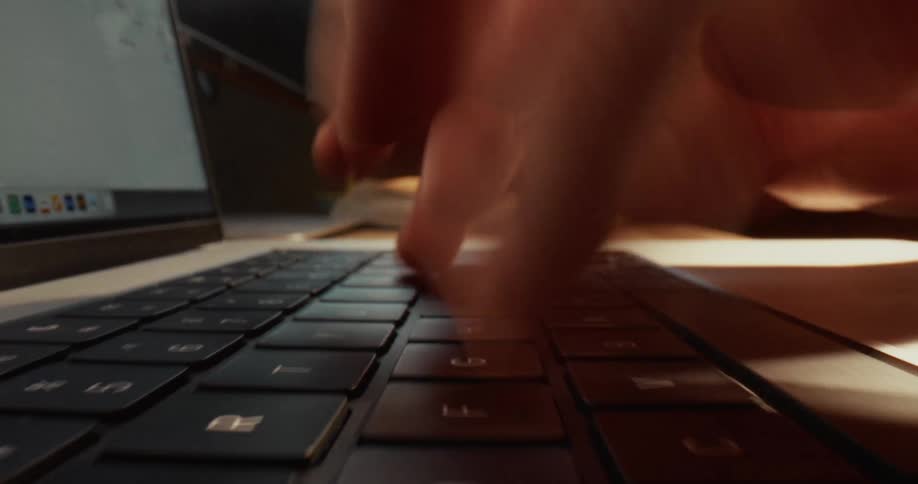 Finger pressing keys on a laptop keyboard in a work environment