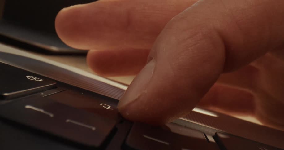 Hand typing quickly on a laptop keyboard on a work desk