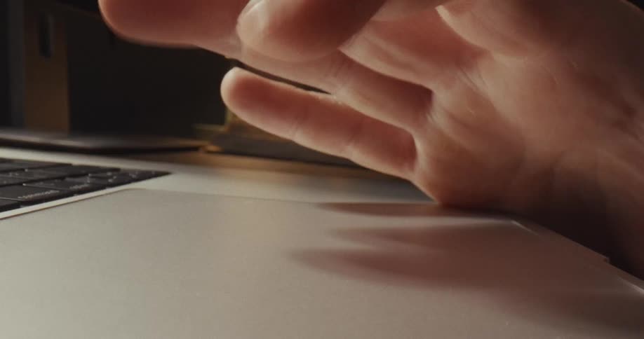 Laptop keyboard meets the trackpad area this line creates a clear boundary between the textured keys on the left and the smooth matte surface of the trackpad where the fingers are resting