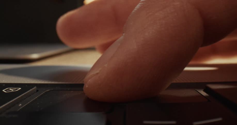 A close up view shows a person pressing a key on a laptop keyboard