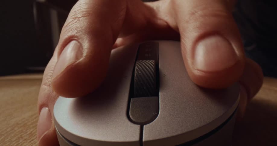 Hand on a computer mouse turning the scroll wheel with their finger