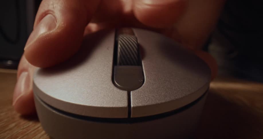 Hand grips and clicks a mouse button on a wooden surface