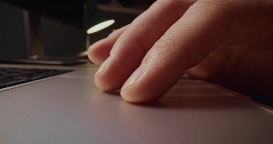 Finger sliding across a laptop trackpad on a work desk