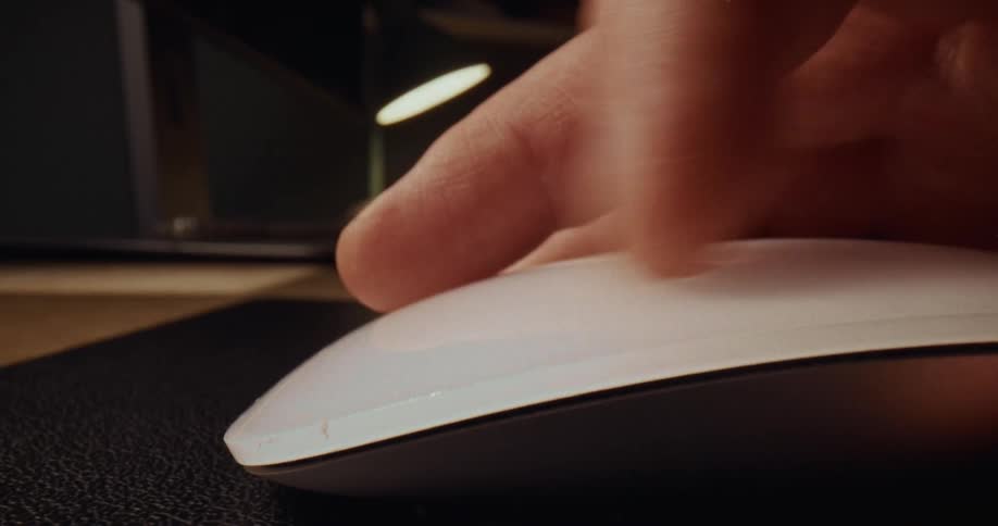 Hand using a mouse on a desk surface in a work environment