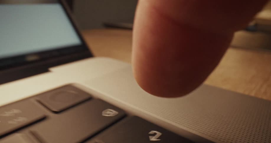 A close up view shows a finger pressing keys on a laptop keyboard
