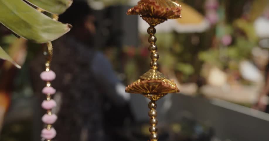 Decorative hanging ornaments beside green leaves in an outdoor setting