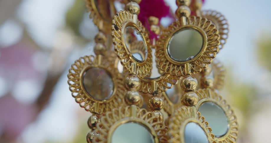 Garland of mirrors with golden frames and beads outdoors during day time
