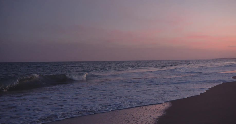 Ocean waves breaking on the beach at sunset
