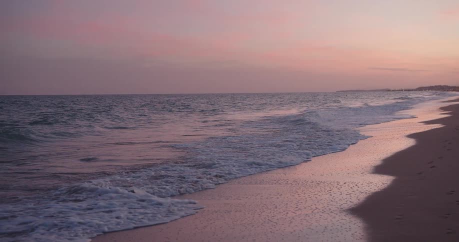 Ocean waves moving across the shoreline at dusk