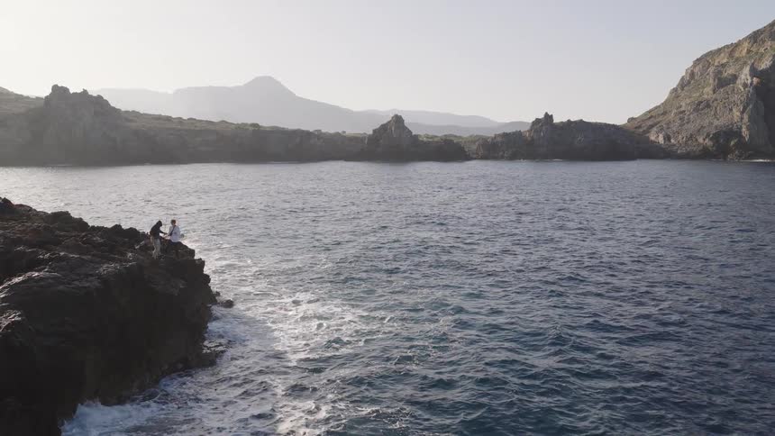Two people are standing on an island looking at the water
