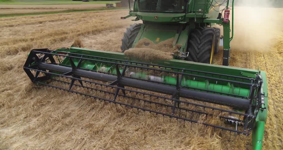 Combine harvester at work on a farm with hills and vegetation on the background outdoors during day time