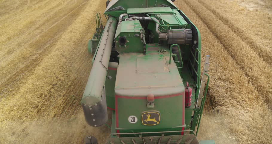 Agricultural harvester seen from behind moving through a field during harvesting