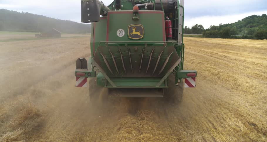 Truck plowing a farm field as traffic moves on a street in the distance