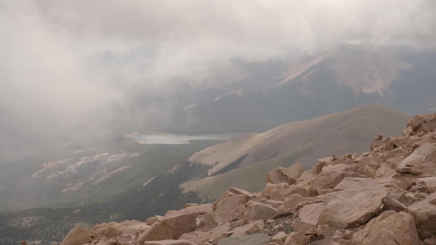 Clouds pass over the side of a mountain