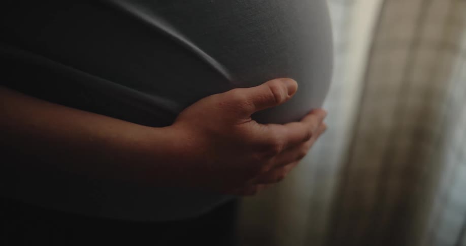A pregnant woman gently rubs her stomach