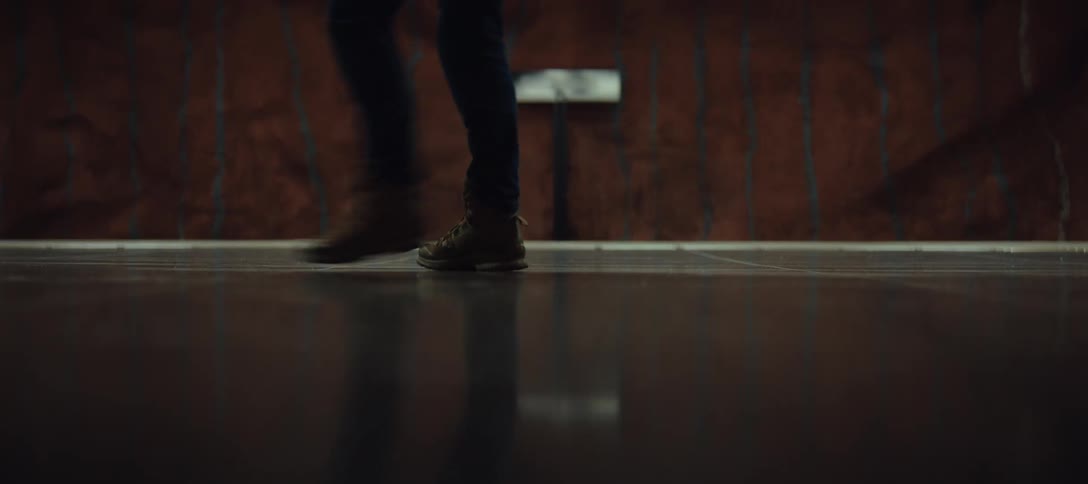 Person walking in boots across a reflective indoor floor