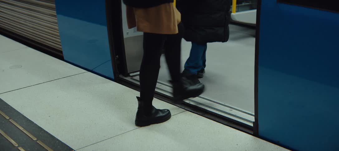 People step through the open doors of a subway car