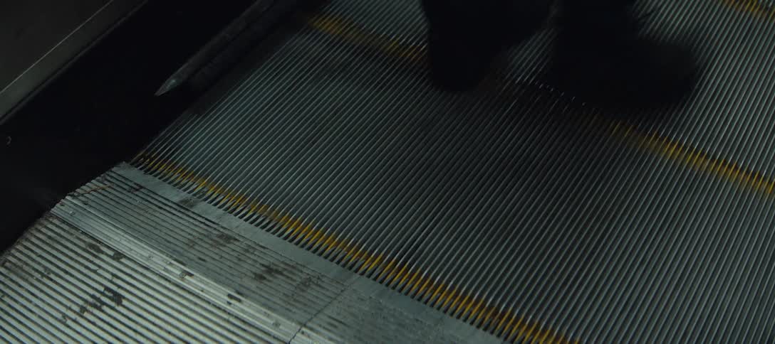 Feet walking on escalator steps in a station