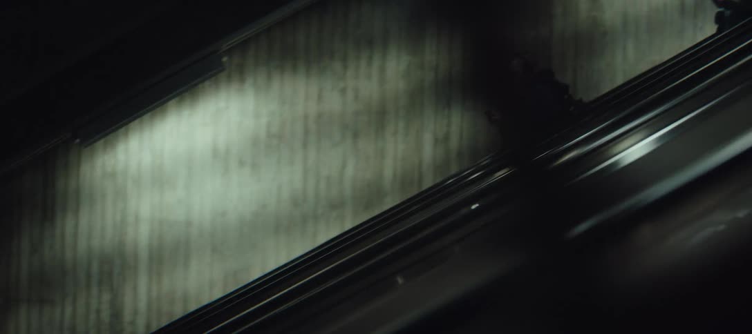 Three people are descending an escalator in an underground station
