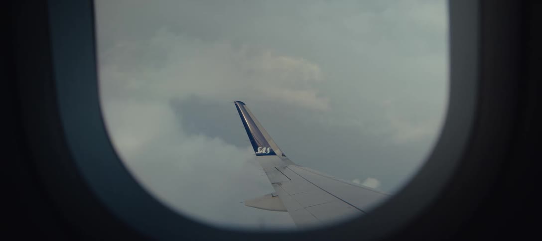 An airplane window with the wing visible outside as the plane flies through the air