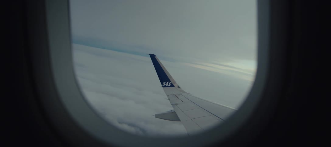Airplane wing visible through the window during flight above a thick cloud layer