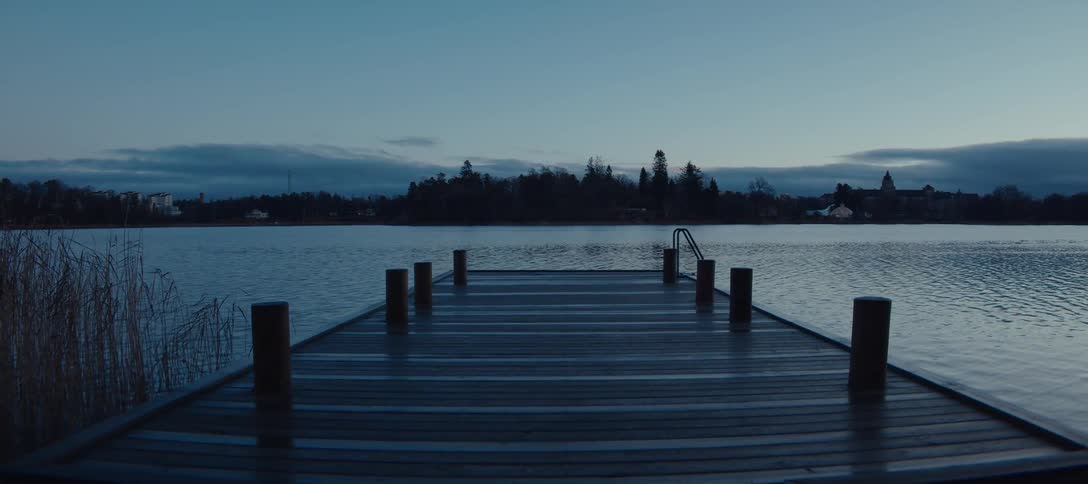 Wooden dock extends over calm lake at dawn
