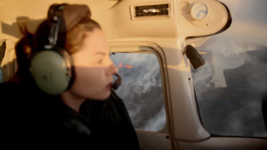 The pilot looks out the window as she flies