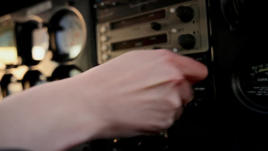 The pilot turns switches in the cockpit