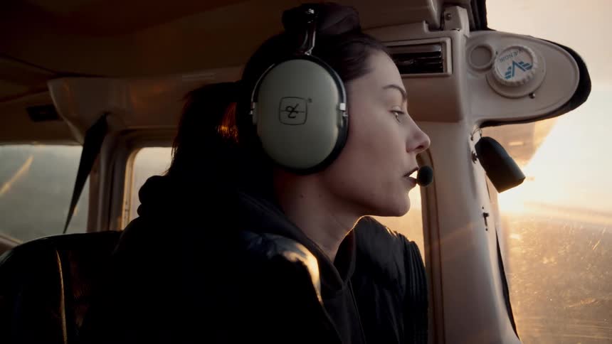 Woman wearing a headset piloting a light aircraft during a sunset flight