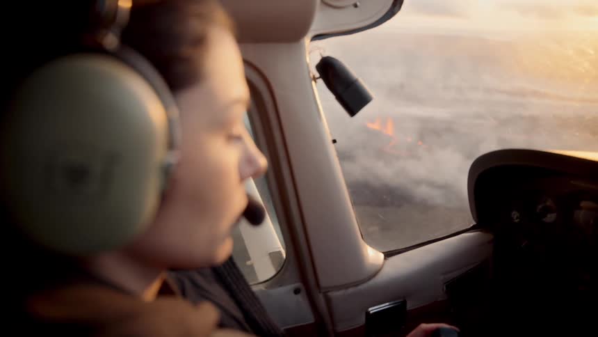 Closeup shows pilot with headset watching outside during flight in light aircraft