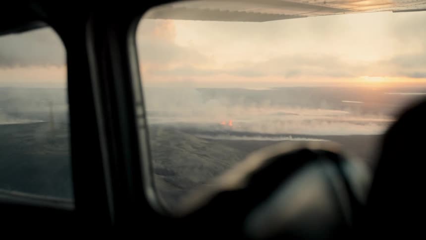 Volcanic activity emits smoke and lava seen from aircraft window