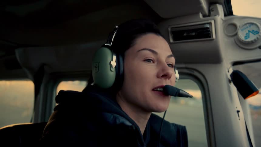 Person with headset communicates during flight in light aircraft with view of airfield at sunset