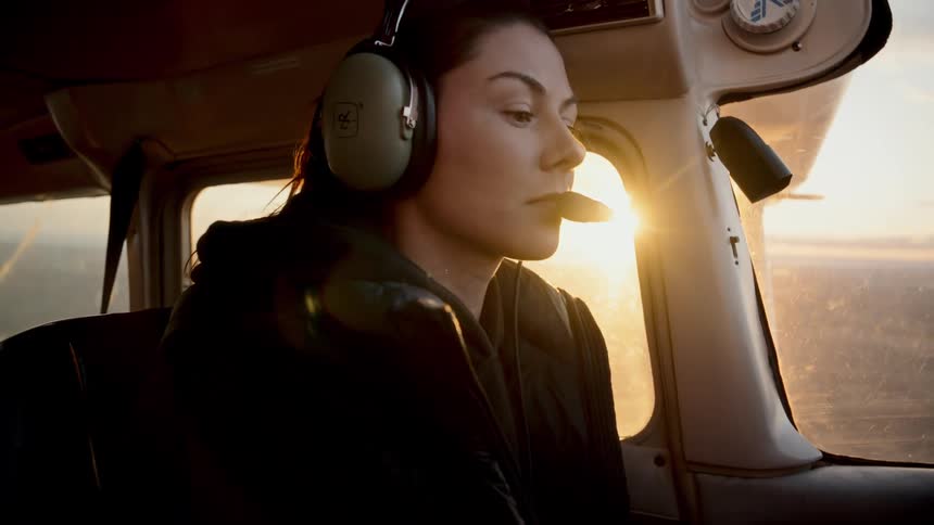 Woman wearing aviation headset and microphone seated in the cockpit of a small aircraft during sunset flight