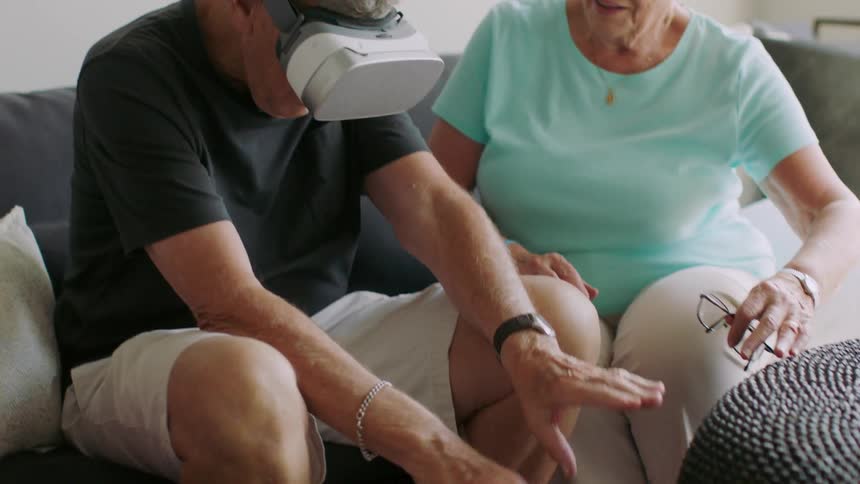 A man wearing vr glasses looks down and paddles his hands