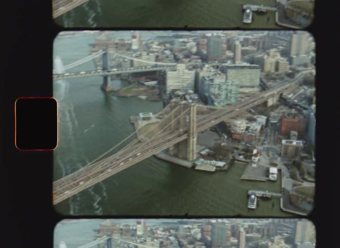 Aerial view of suspension bridges connecting urban areas over a river with dense buildings surrounding them