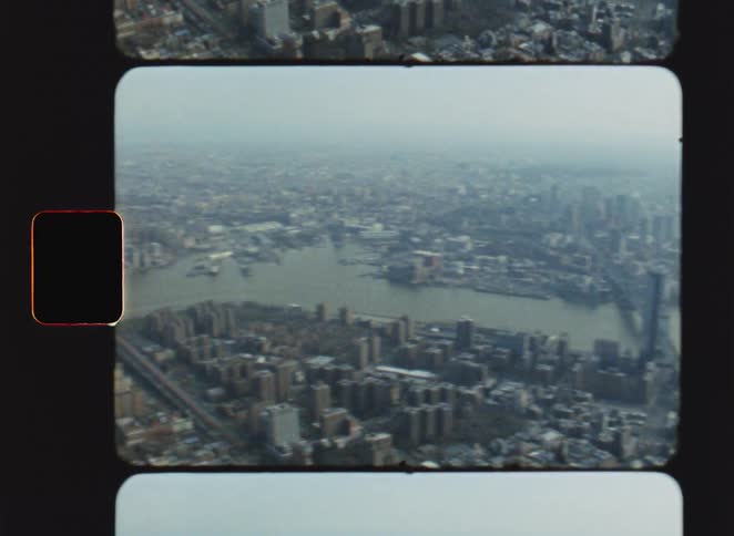 Aerial view shows suspension bridge linking dense urban areas with river at center