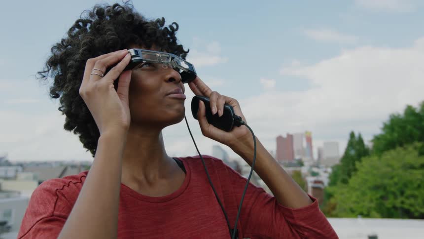 A woman looks up at the sky through some glasses