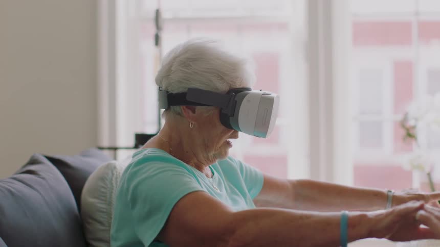 Am elderly woman is talking and gesturing while wearing a vr headset