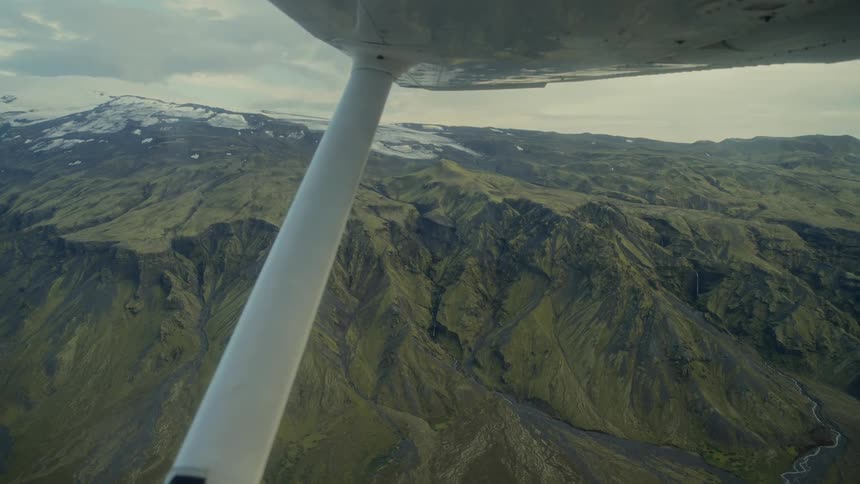 The plane wing sways as it travels over the mountains