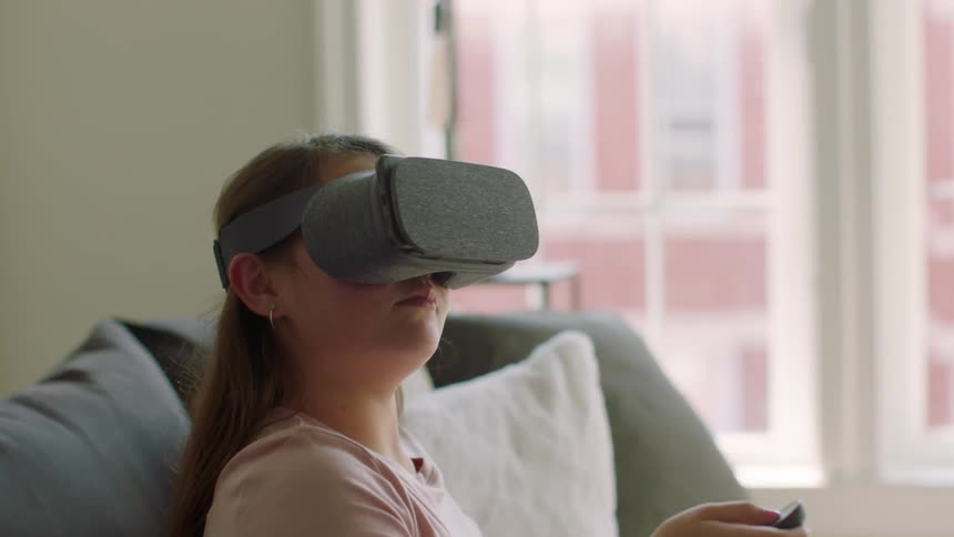 A woman sits on a couch wearing vr glasses