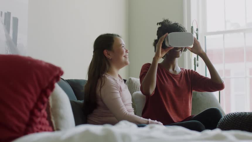 A woman uses a virtual reality headset while sitting on the couch
