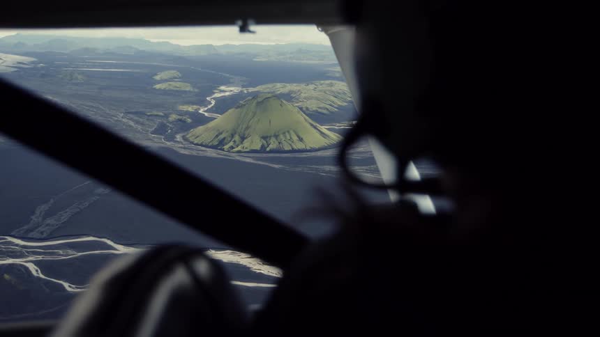 Silhouette of a person in an airplane with a view of volcanic mountains